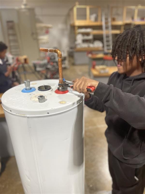 Henry Ford HS senior Sterlin Saunders attaches a hot water line to a hot water tank at Randolph Career Technical Center on March 5. Photo by Elijah Neal/Mustang Voice