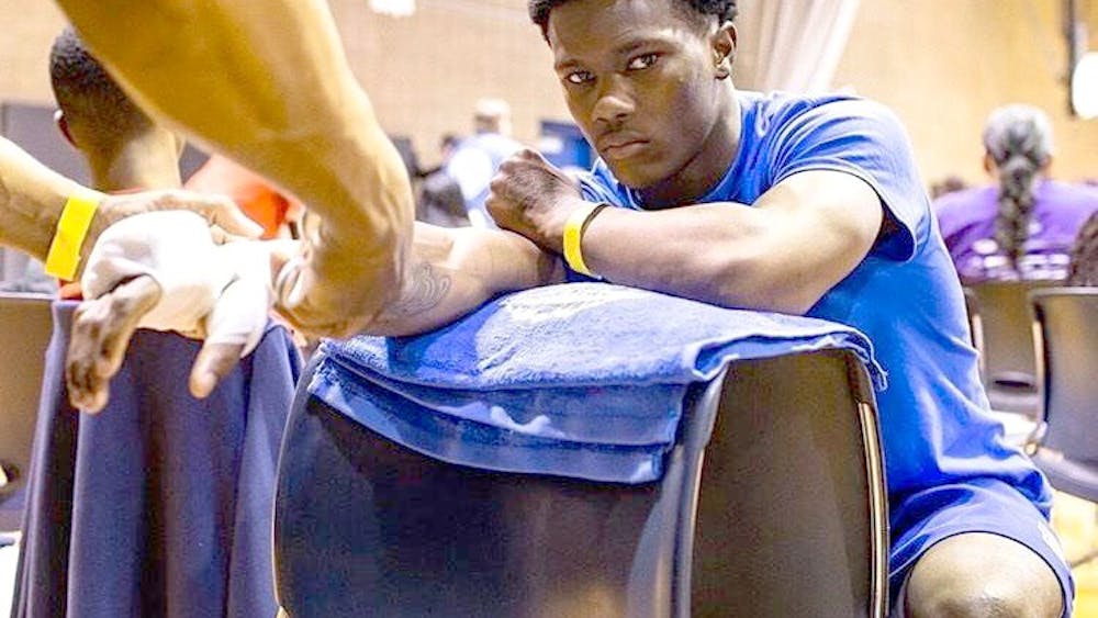 Kahlil Harvey wraps Ferris Dixon’s hands before a fight at Roberto Clemente Recreation Center on June 1. Harvey is Dixon’s uncle and his trainer. Dixon won his fight by unanimous decision after three rounds. Photo courtesy of Greg Dixon.