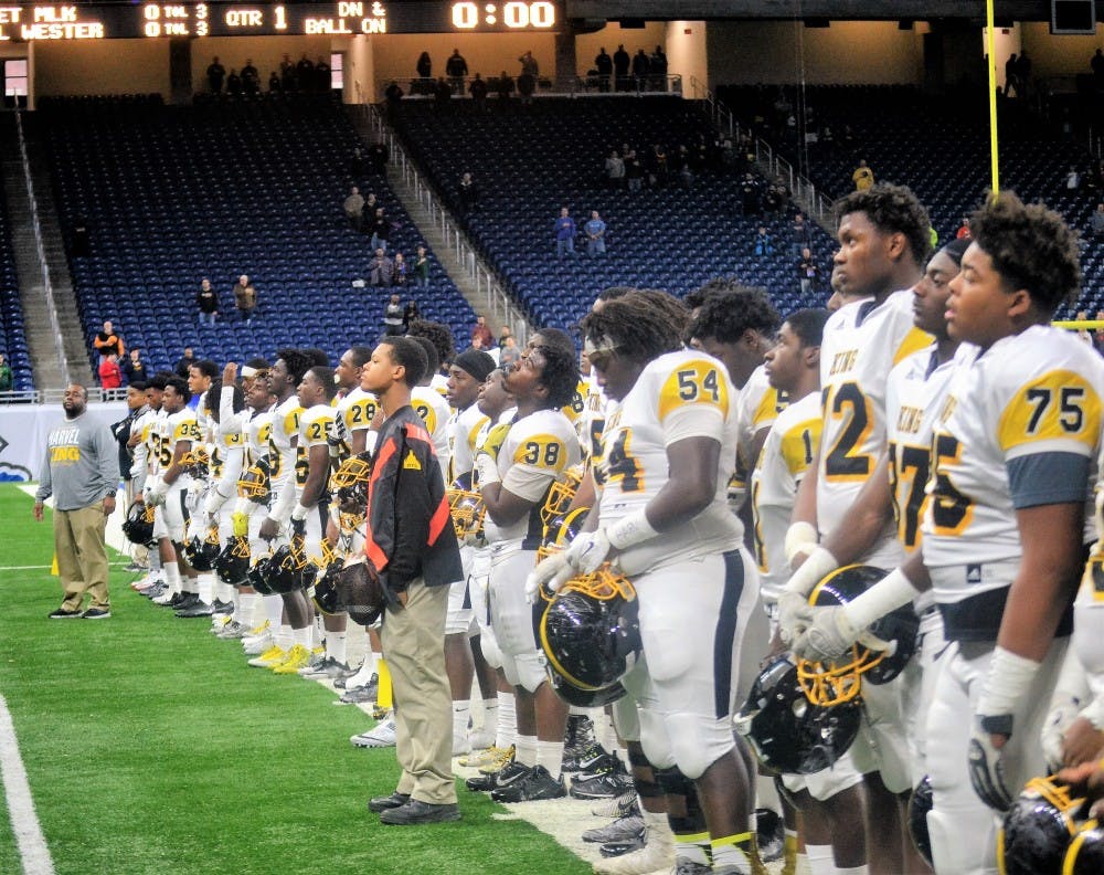Crusaders salute the flag during the singing of the National Anthem.