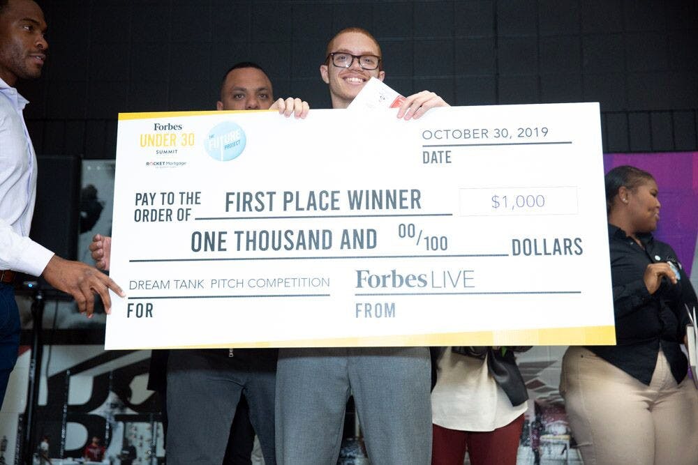 Davon Schelgel holds the first place check from the “Shark Tank”-style competition. Competitors had to pitch their business ideas to win a $1,000 starting check provided by Forbes. Courtesy photo.