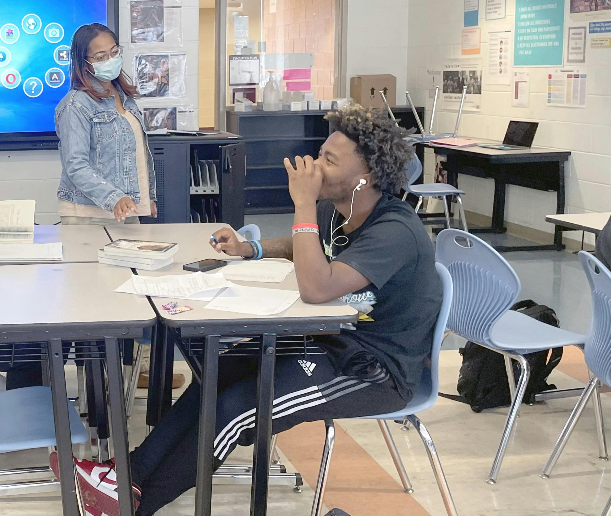11th grade teacher Timmi Gordy-Oliver, Mumford class of ’95, helps Iasiah Stone with his novel project on Nov. 3.  Mumford was the best experience of my teenage years,” Oliver said. “The whole neighborhood had school spirit and a sense of community.” Photo by Saria Uddin
