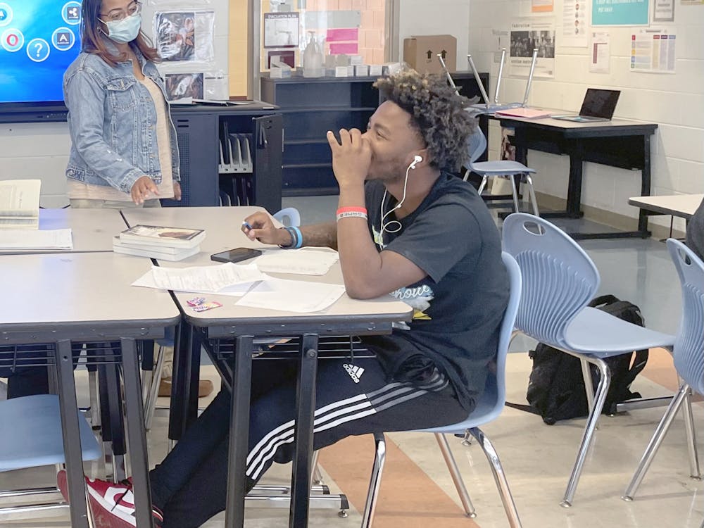11th grade teacher Timmi Gordy-Oliver, Mumford class of ’95, helps Iasiah Stone with his novel project on Nov. 3.  Mumford was the best experience of my teenage years,” Oliver said. “The whole neighborhood had school spirit and a sense of community.” Photo by Saria Uddin
