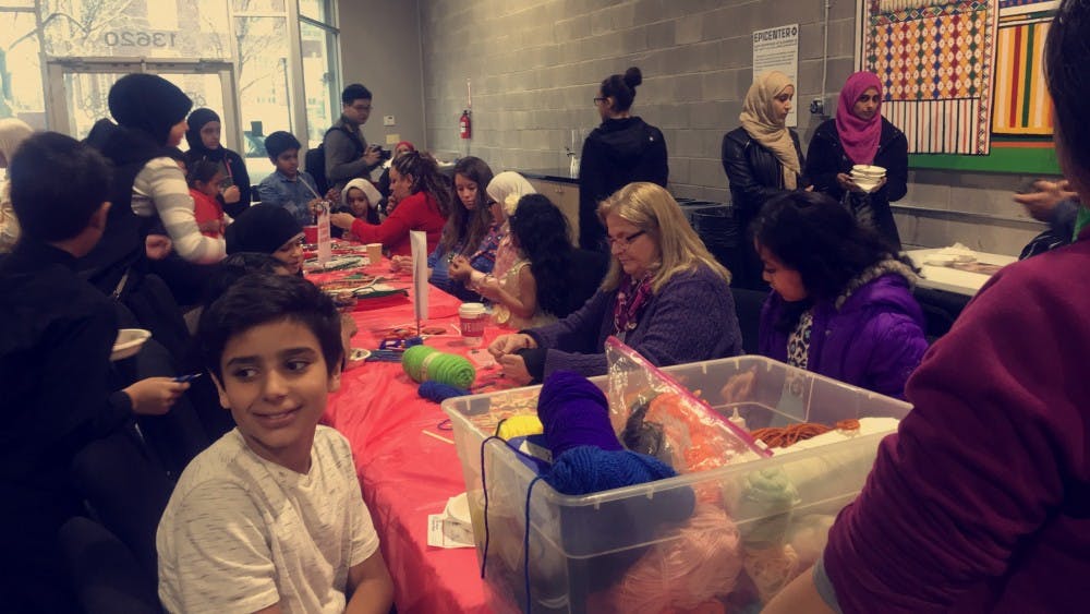 <p>Cristo Rey staff and students help children make crafts&nbsp;at the National Arab American Museum's Christmas party.</p>