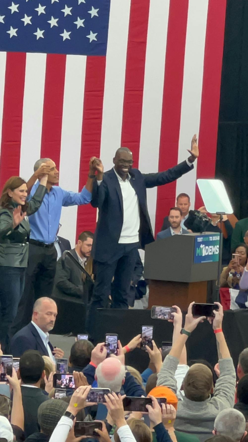 Gov. Gretchen Whitmer, former President Barack Obama and Deputy Gov. Garlin Gilchrist hold hands and raise their arms, to celebrate a successful campaign event. Courtesy photo.