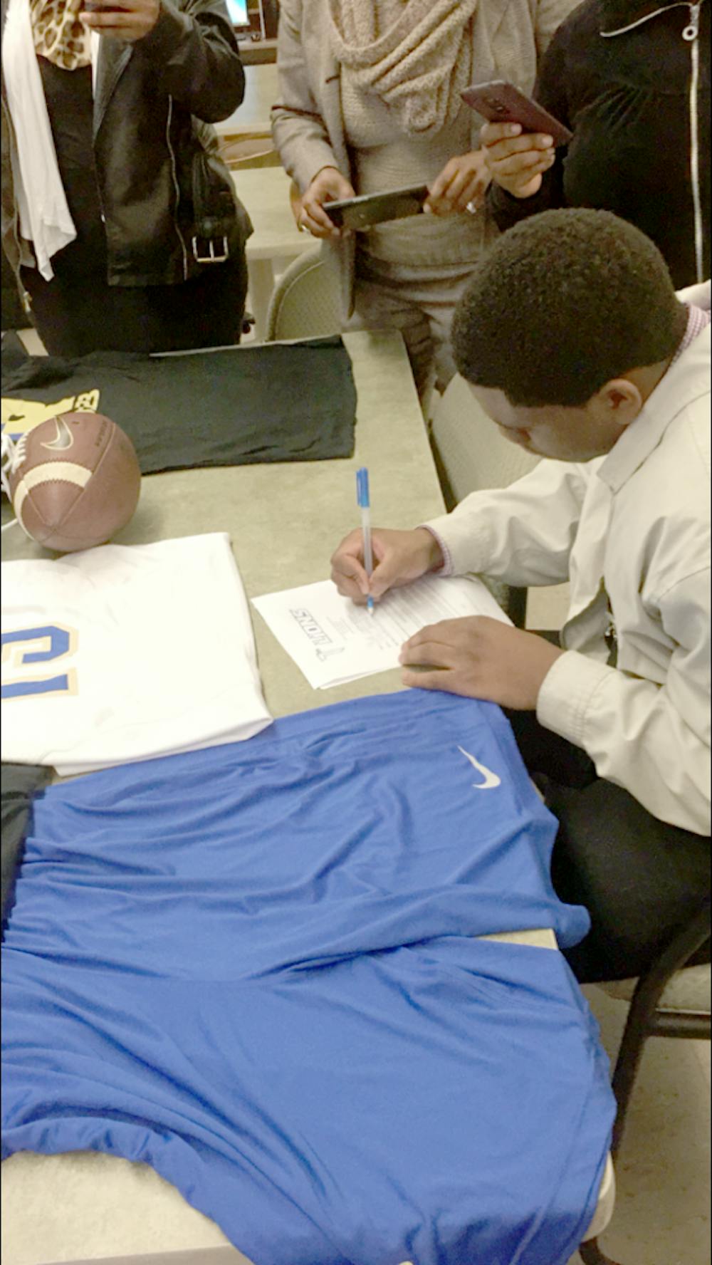 <p>Douglass quarterback Elijah Juan Pearcy signs his letter of intent to play football at Trinity Bible College in North Dakota.</p>