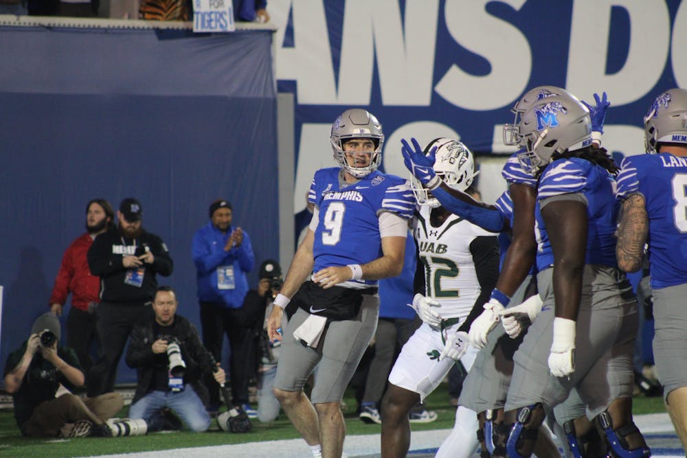 Memphis quarterback Seth Henigan (left) celebrates a touchdown run with his teammates.