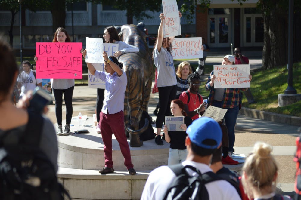 <p>Students hold protest signs in front of the UC Oct. 12&nbsp;</p>