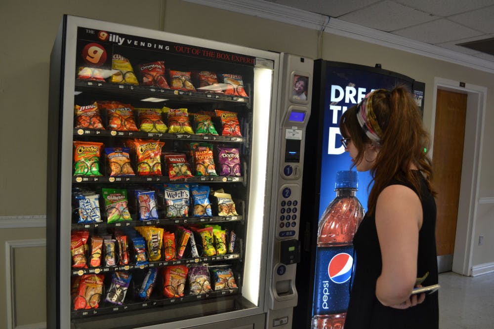 <p>Lauren Angelillo, 18-year-old music education major, buys a snack from the vending machines in Rawls Hall. The machines in that building were repaired on Tuesday but have been notorious for taking students’ money without giving food in the past.&nbsp;</p>