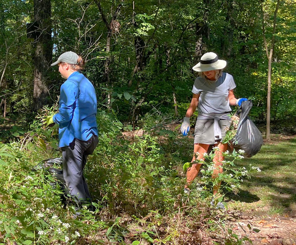 Volunteers pull weeds and stuff them into trash bags at the Memphis Botanic Garden's Weed Wrangle event early Friday morning.