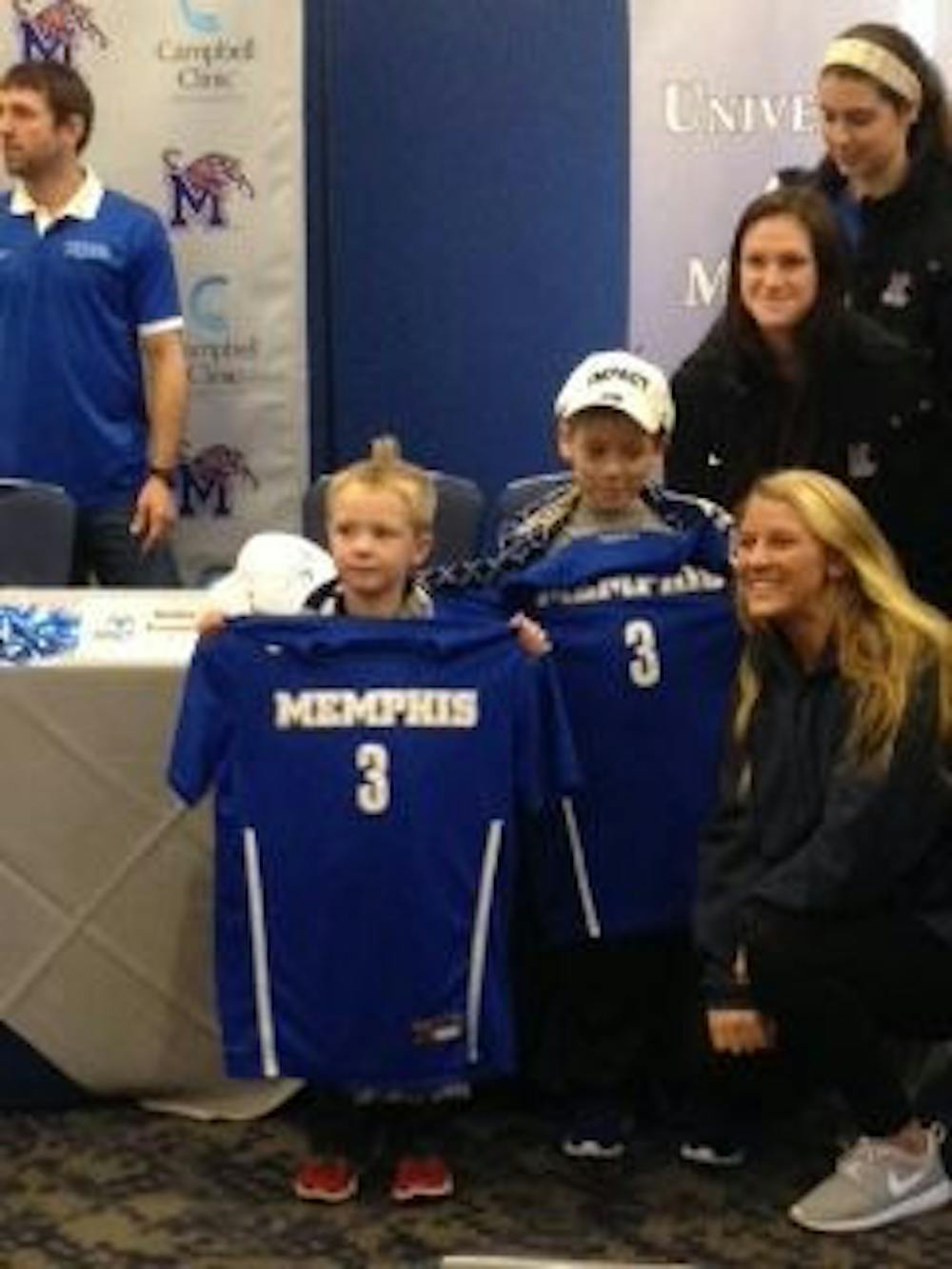 <p class="p1"><strong>Maddox and Brooks pose with their jerseys next to Sydney Kingston, Elizabeth Woerner, and Lauren Sobral of the women’s soccer team.&nbsp;</strong></p>