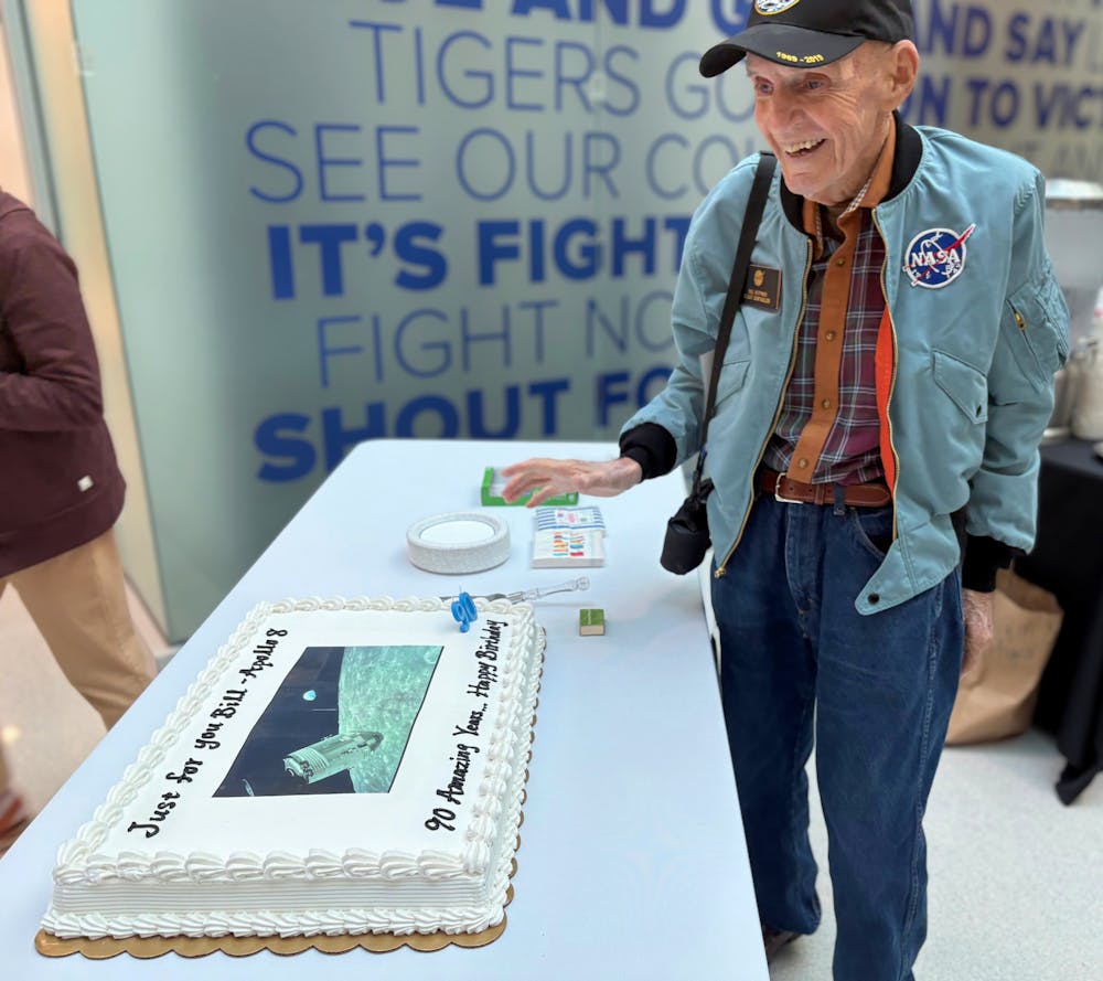 <p>Bill Weppner, former Apollo flight controller, smiles beside his 90th birthday cake decorated with an image from Apollo 8.</p>