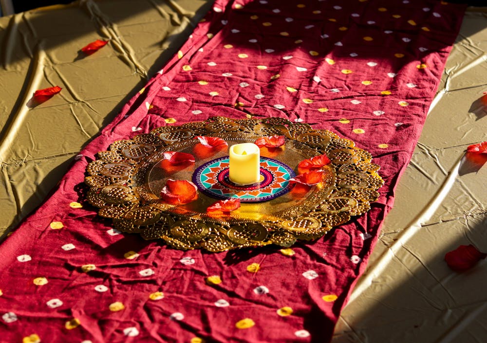 <p>A decorative candle and rose petals sit atop a gold plate during the University of Memphis Diwali celebration in the Rose Theater.</p>