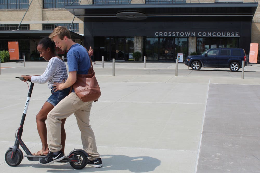 <p>A couple decides to double up on one scooter and try to ride around the Crosstown Concourse courtyard area. BIRD scooters have become a fun new form of transportation to get around the city.</p>