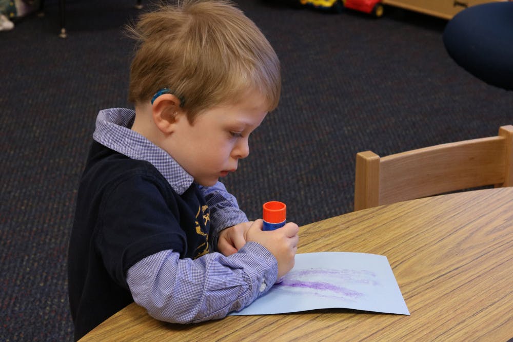 <p>Memphis Oral School Preschooler Landon Hays glues the back of his paper. The son of Development Director Lauren Hays enrolled for the sound beginnings program in 2014 and continued with the preschool program this year.</p>