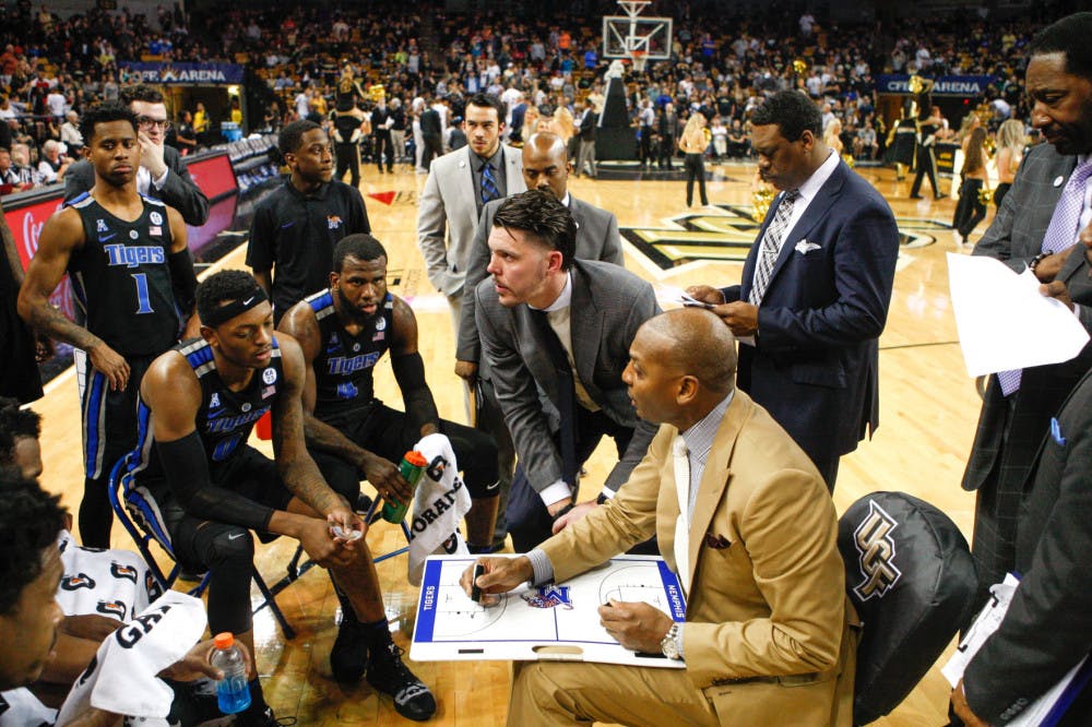 <p class="p1"><span class="s1"><strong>Head coach Penny Hardaway (tan suit) huddles with his team.</strong></span></p>