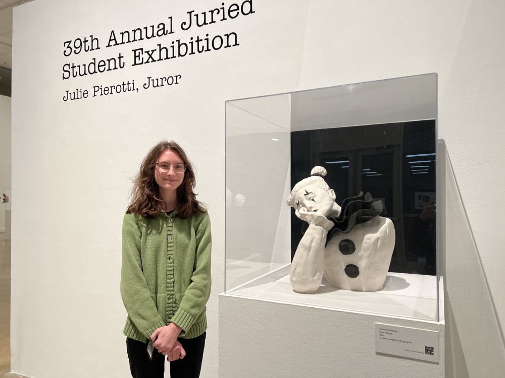 <p><span>Anna Clements, a sophomore studio art student, stands next to her ceramic sculpture, "Poor Pierrot," which serves as the focal point for this year's Juried Student Exhibition exhibit.&nbsp;</span></p>