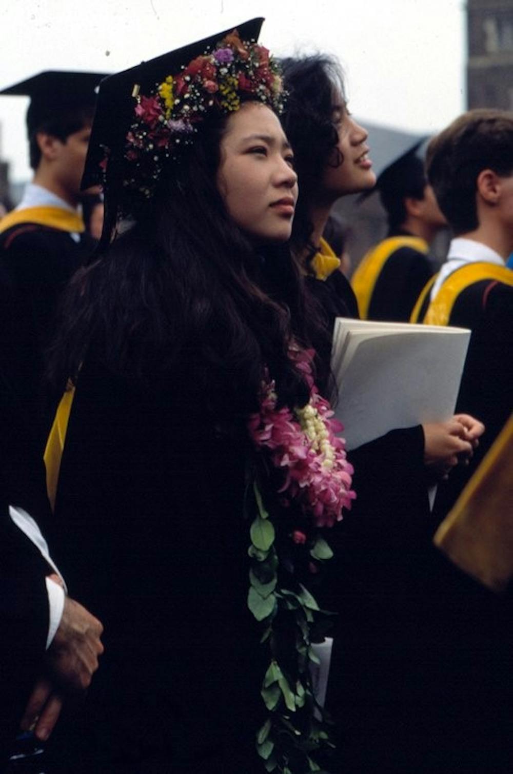 Commencement-1982-woman-graduate-in-cap-and-gown-festooned-with-flowers