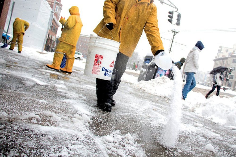 Allston, Feb. 5, 2014 -- Valdir Dossontos, center, throws salt onto a Commonwealth Avenue sidewalk in Allston, MA, while other workers around him shovel. Photograph by Carolyn Bick. © Carolyn Bick/BU News Service 2014.