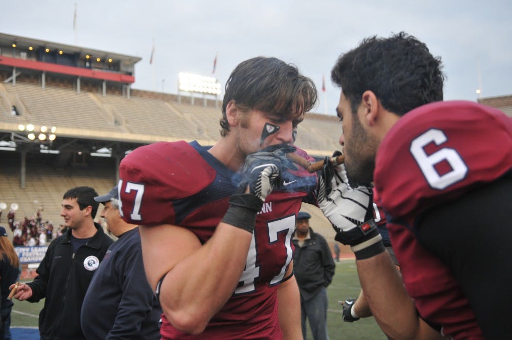 	Sophomore receivers Mitchell King (left) and Cole Stern (right) celebrate Penn’s Ivy championship with cigars at midfield Saturday after the Quakers beat Harvard, 30-21.