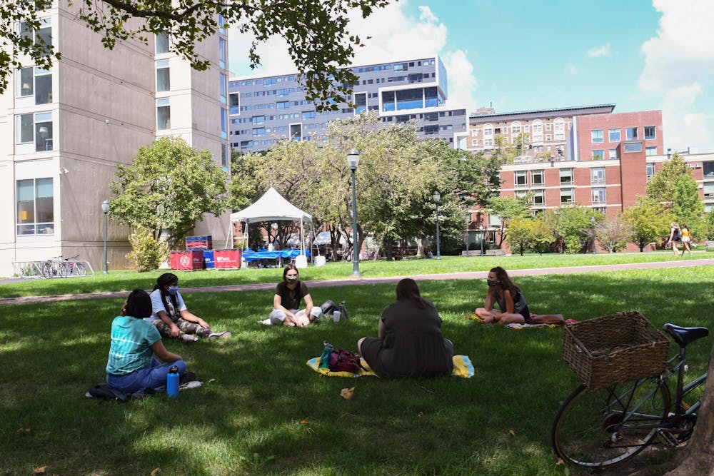 friends-gather-social-distance-circle-high-rise-field-coronavirus-campus-fall-2020