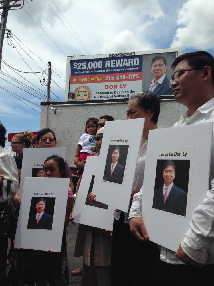 The Ly family stands under the new billboard during the press conference, holding posters that read "Justice for Don Ly."