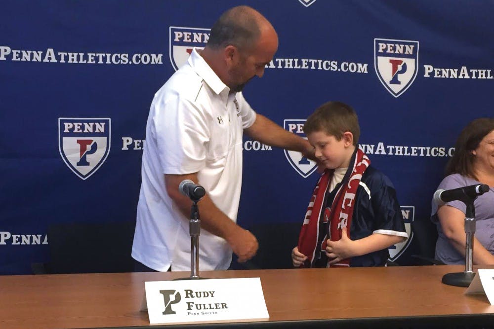 Coach Rudy Fuller gives Penn men's soccer's newest member Tanner Falato a Penn soccer scarf and jersey at a press conference Monday afternoon in conjunction with the Friends of Jaclyn Foundation