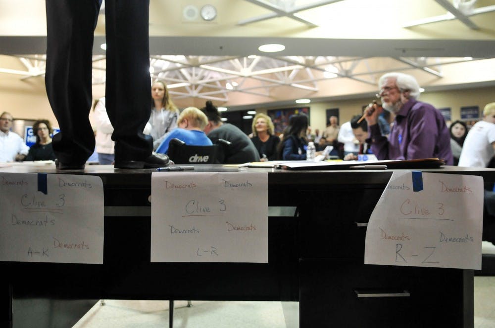 The precinct leader stood on the registration table to speak to the room in Clive, IA. 