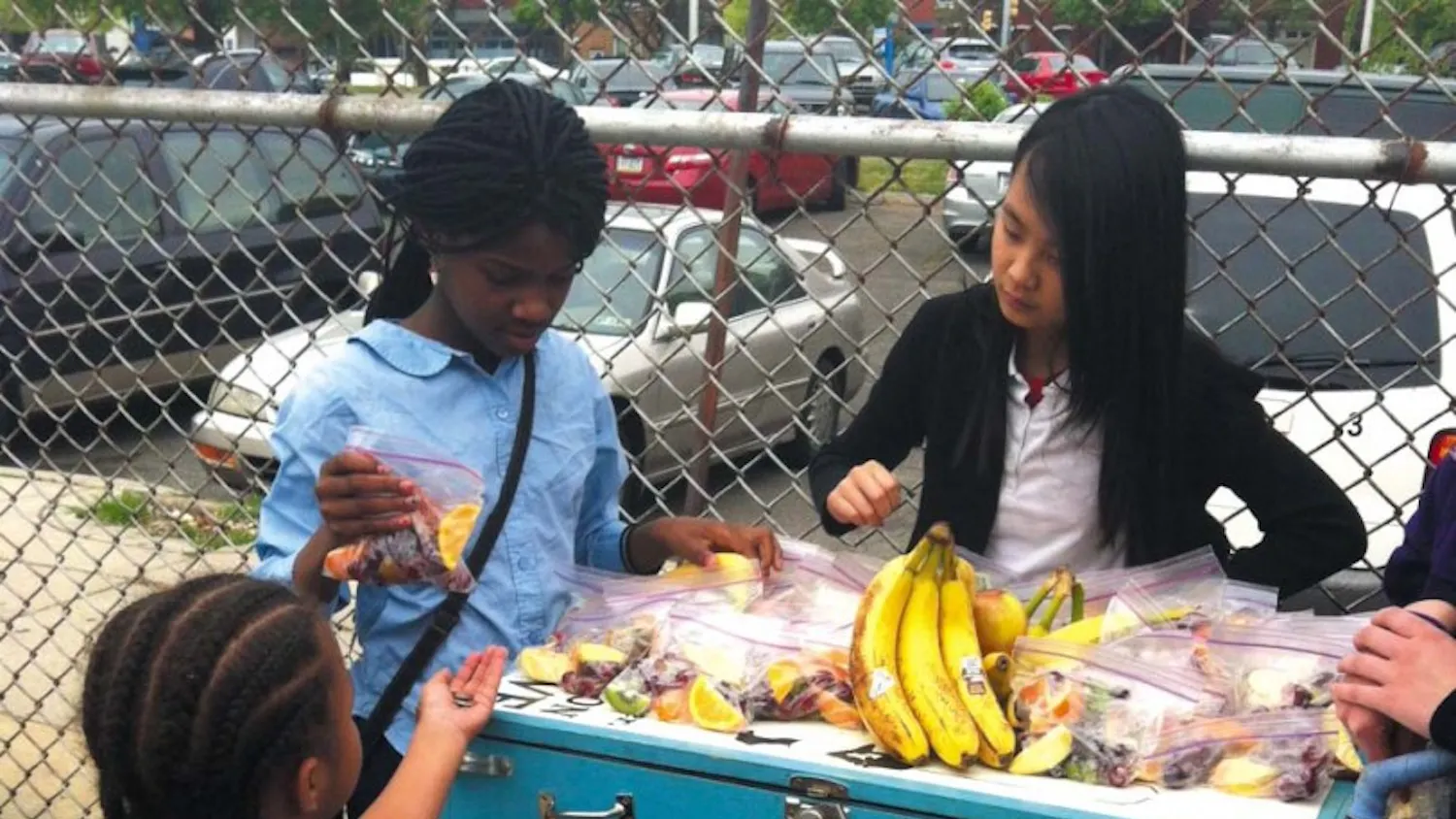 Students work a fruit stand at the now-closed Drew Elementary School in the city. They are using a Youth Urban Mobile Market table, selling fruit and smoothies. Read the full story here.