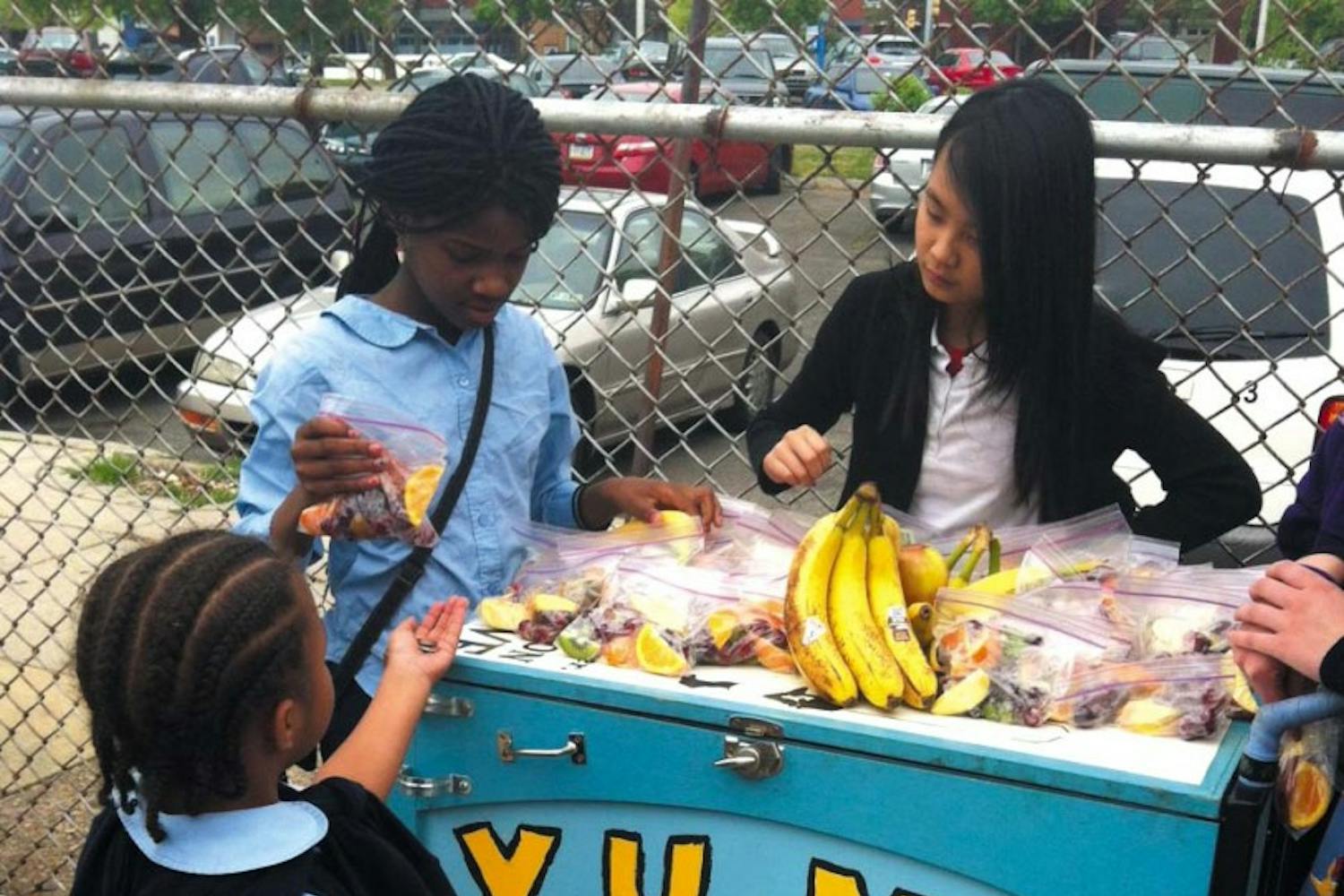 Students work a fruit stand at the now-closed Drew Elementary School in the city. They are using a Youth Urban Mobile Market table, selling fruit and smoothies. Read the full story here.