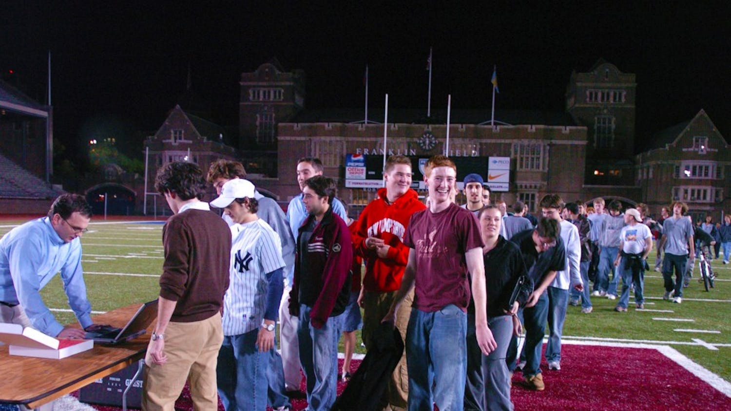 ran 10/12/2004
Zach Rosenblum (left, with NY shirt on) and former DP columnist Justin Rafael (right, with brown sweater) get their tickets at the ticket table at the center of Franklin Field. They were in the first group at The Line.
the line, at franklin field