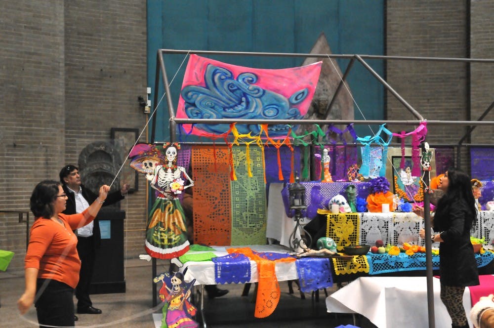 Cesar Viveros builds an altar for the Day of the Dead in the Penn Museum. 