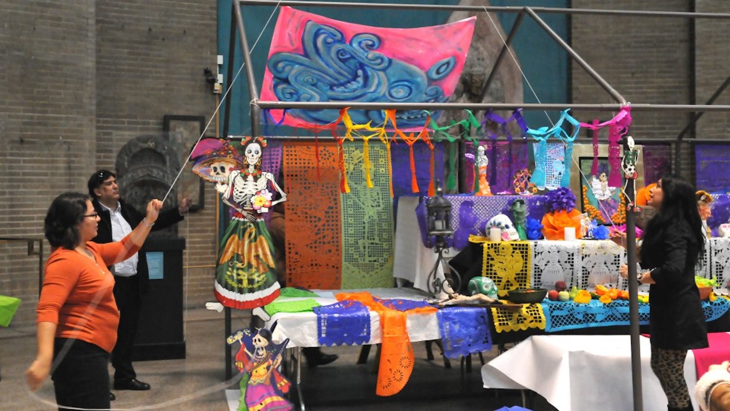 Cesar Viveros builds an altar for the Day of the Dead in the Penn Museum.