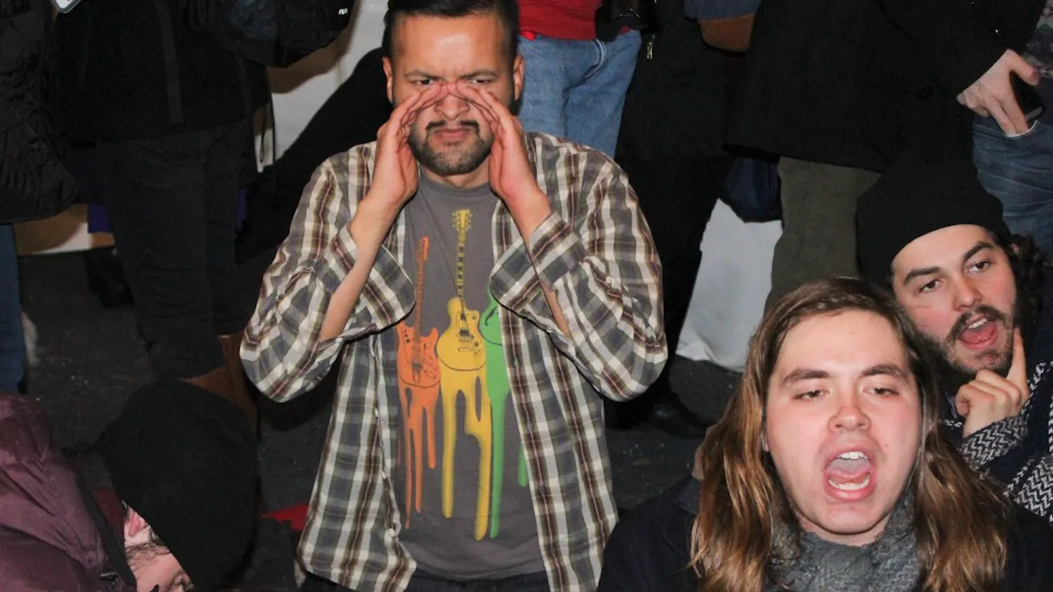 College senior Emanuel Martinez, one of the protest's leaders, sits at President Amy Gutmann's holiday party after Gutmann addressed the crowd.