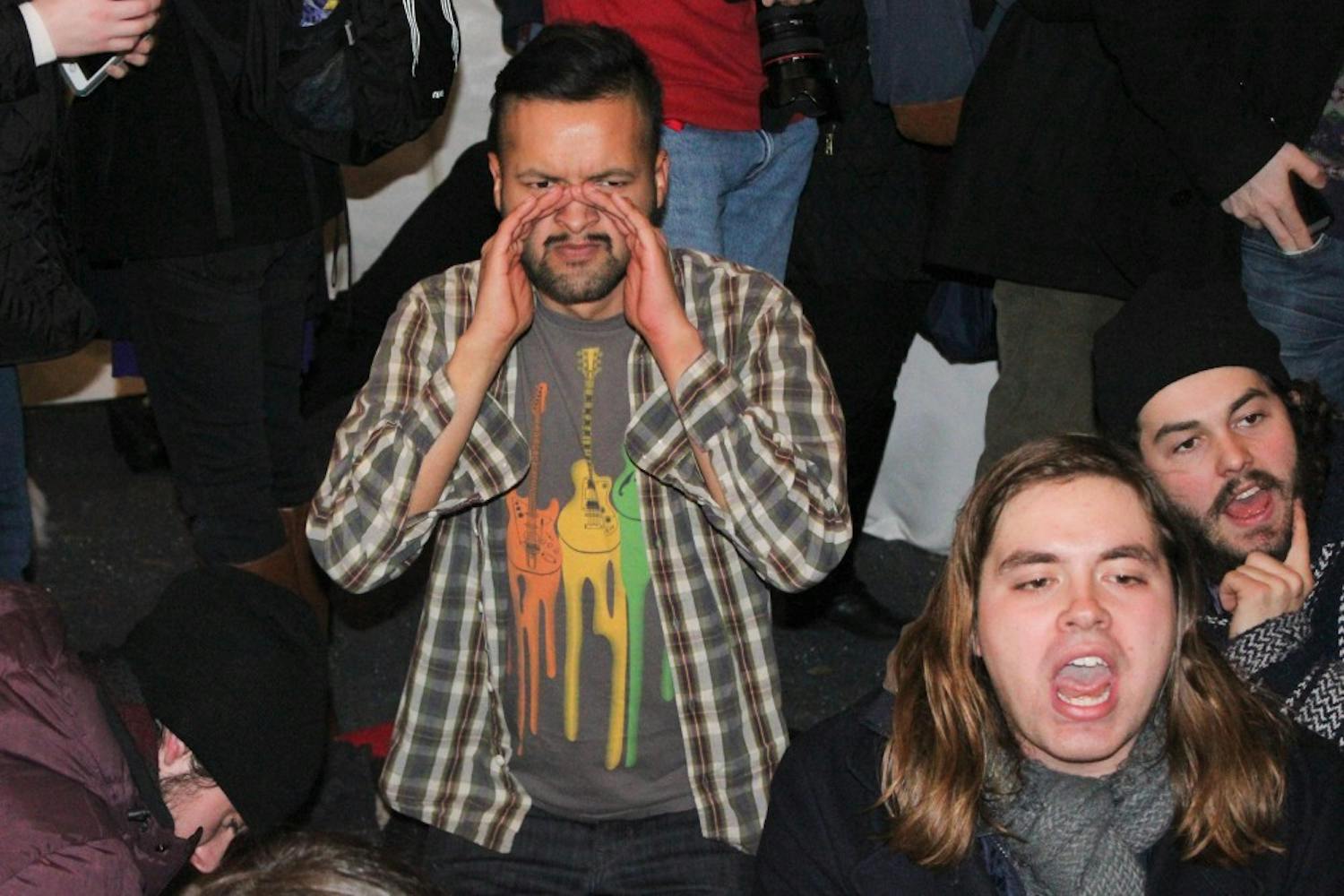 College senior Emanuel Martinez, one of the protest's leaders, sits at President Amy Gutmann's holiday party after Gutmann addressed the crowd.