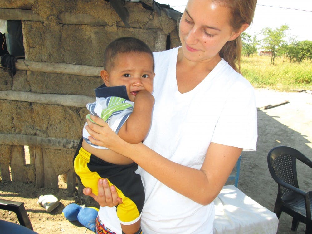 	2012 College graduate Monika Wasik, the field coordinator for the Chaco Area Reproductive Ecology Program, works with a young child in Argentina.