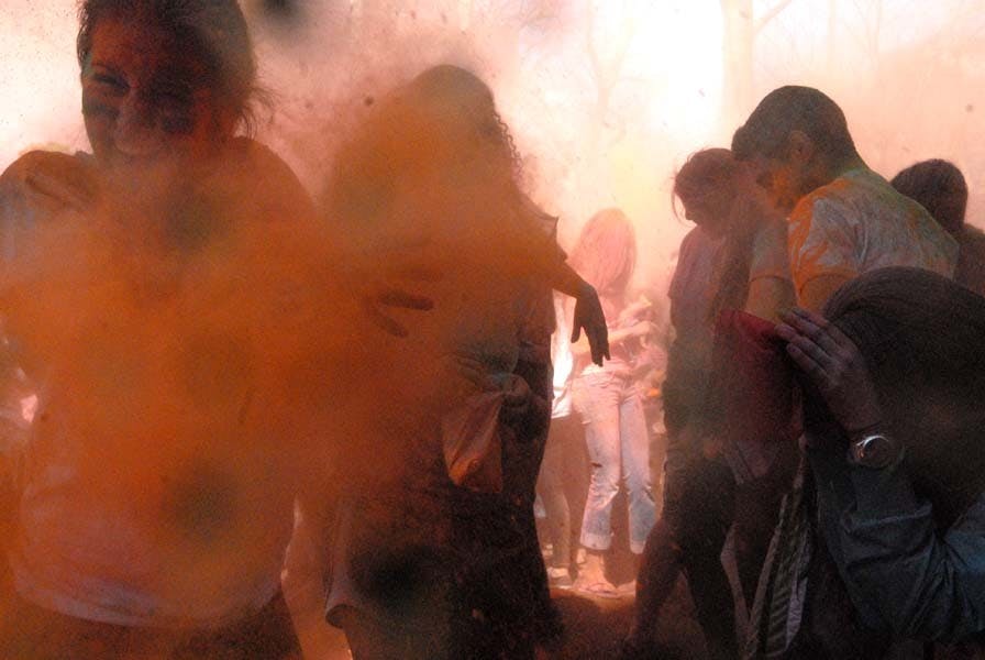 People throw color powders at each other.