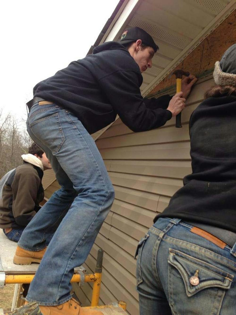 	College freshman Charlie Heinz attaches vinyl siding to a Habitat for Humanity house on an Alternate Spring Break trip in Franklin, West Virginia. 