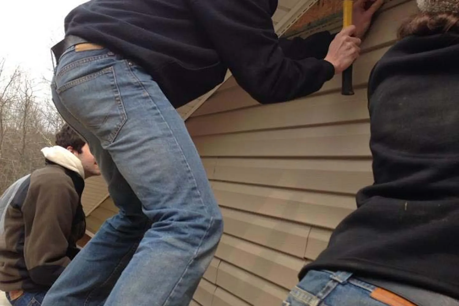 College freshman Charlie Heinz attaches vinyl siding to a Habitat for Humanity house on an Alternate Spring Break trip in Franklin, West Virginia.