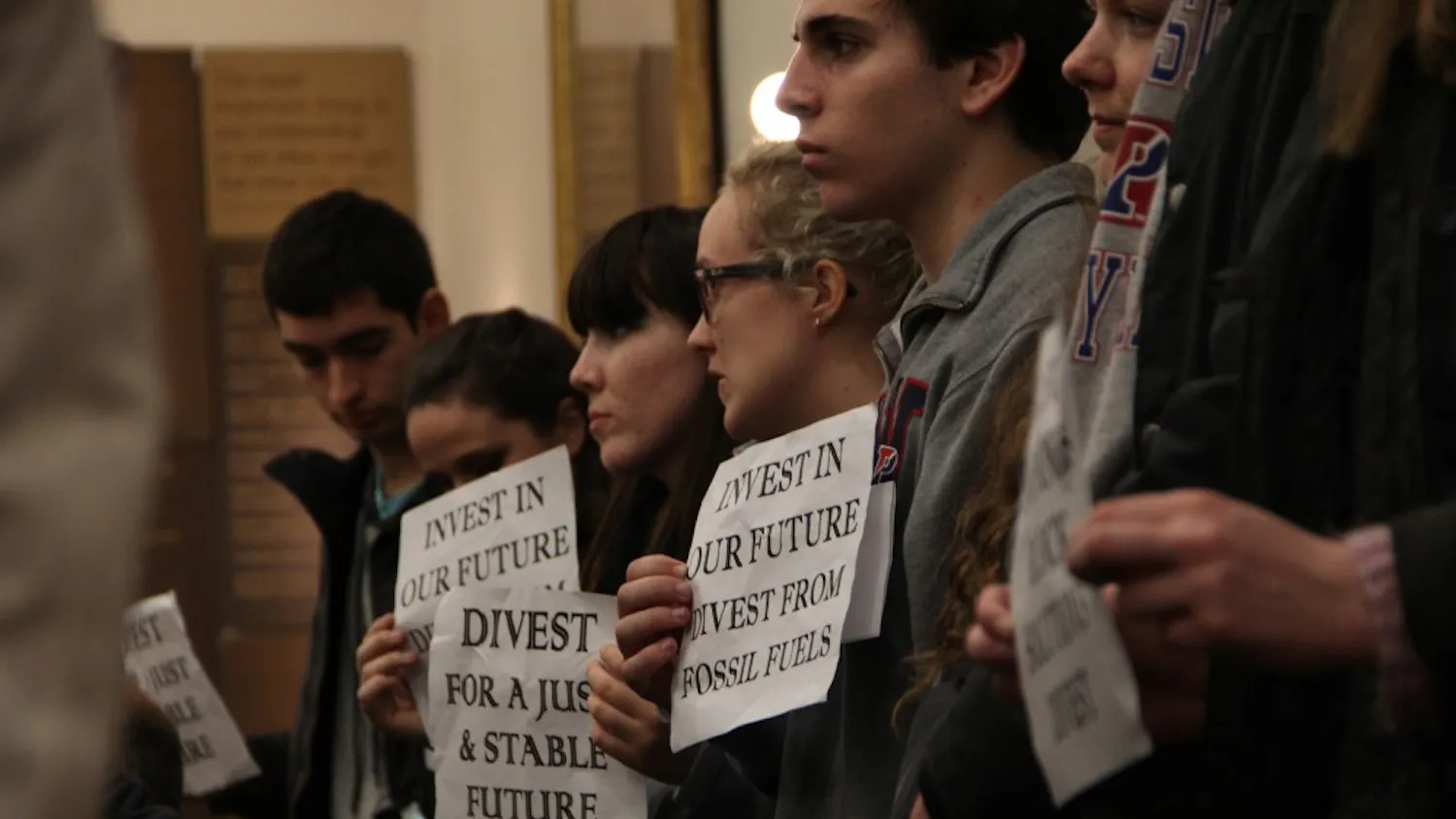 As the forum discussed divestment from fossil fuels, those involved with the rally stood up in silent solidarity baring their weathered signs.