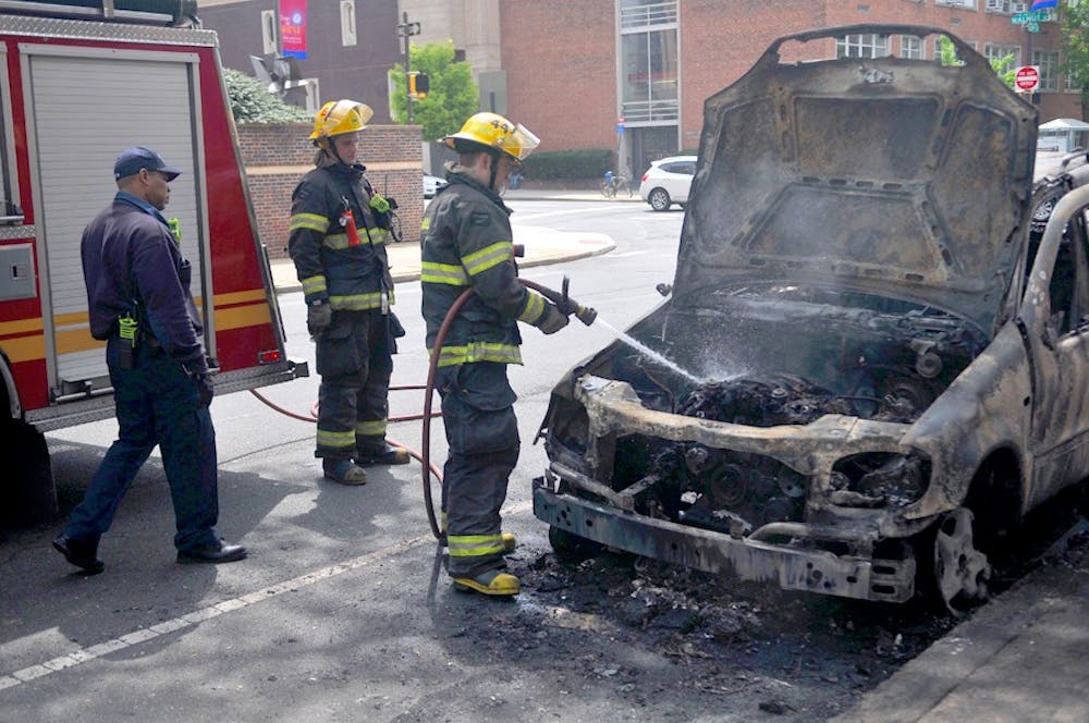 	Firefighters extinguish the flames on a car that caught fire outside of Hill College House this morning.