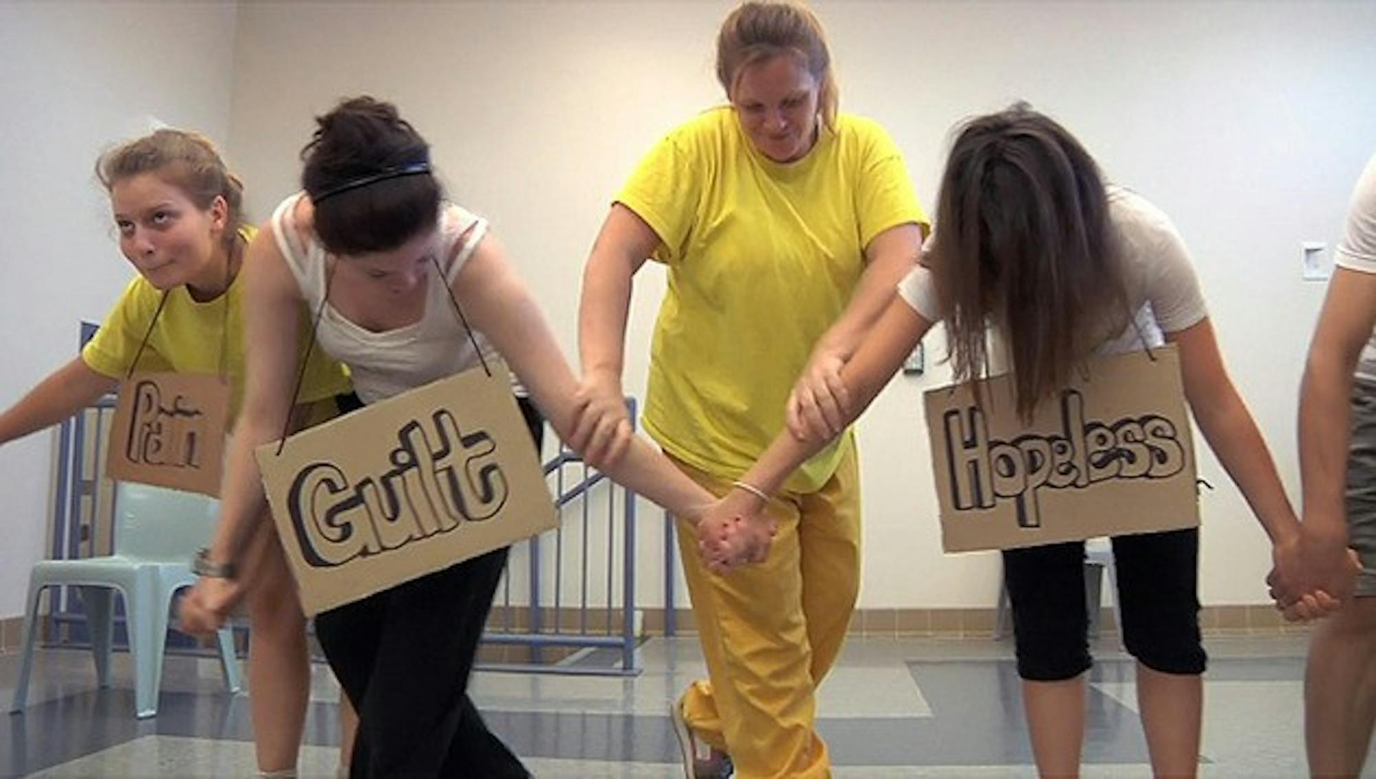 Dartmouth students and inmates hold up cardboard signs as part of their theatrical production.