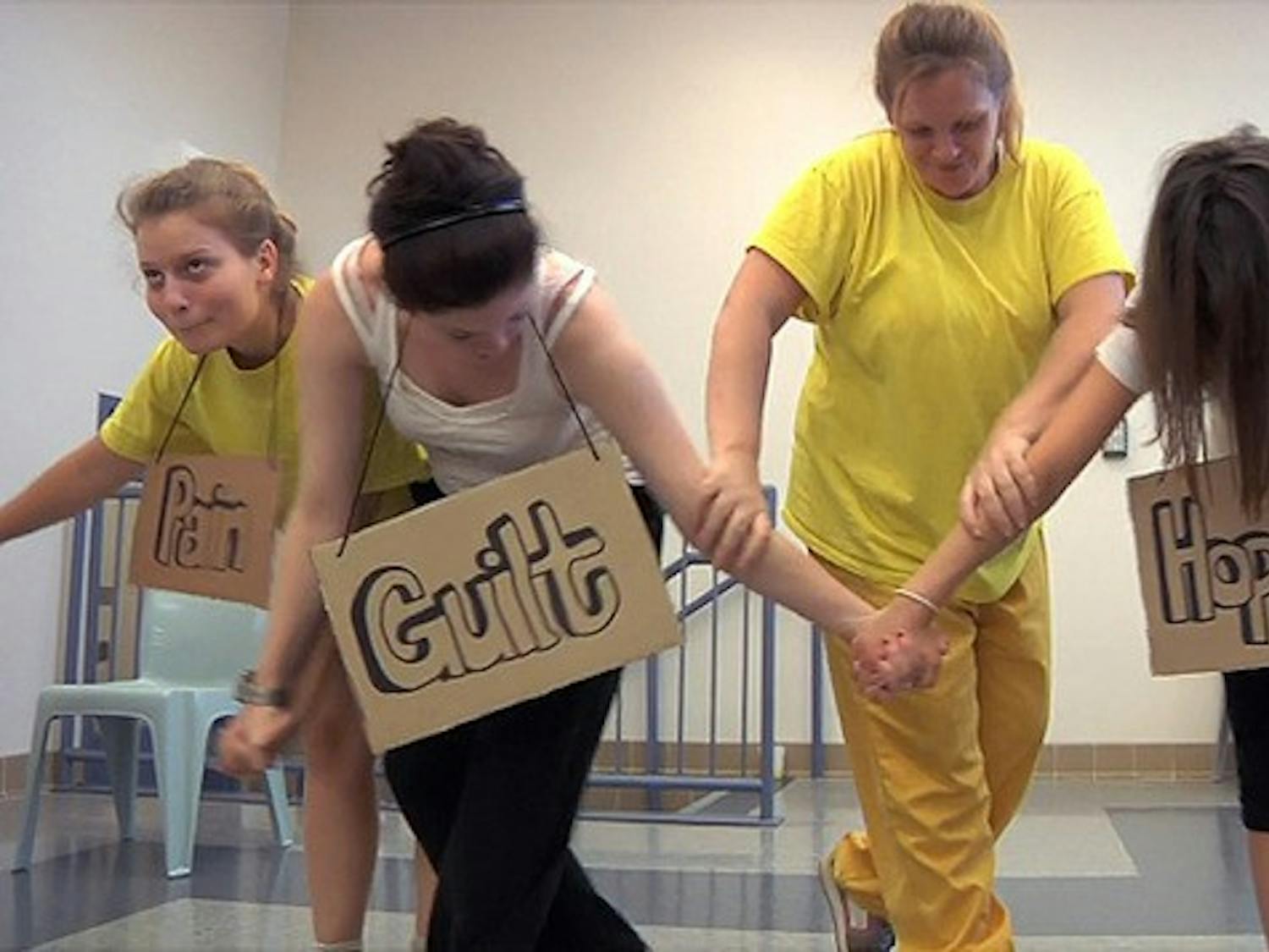 Dartmouth students and inmates hold up cardboard signs as part of their theatrical production.