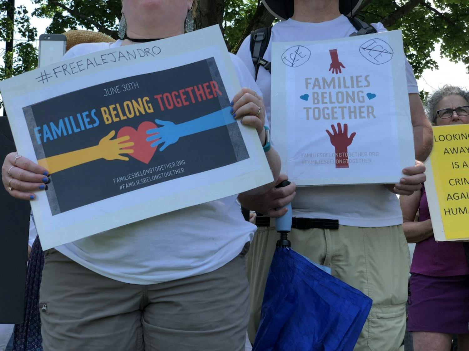 Community members held signs as they gathered on the Green to protest the Trump administration's immigration policies.
