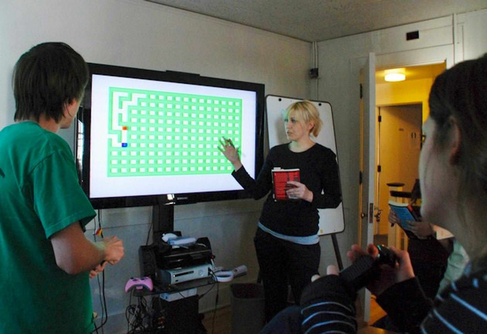 Professor Mary Flanagan and her students examine a vintage video game in the newly-opened Tiltfactor Lab, a game design center in North Fairbanks Hall that houses many antique and modern gaming consoles.