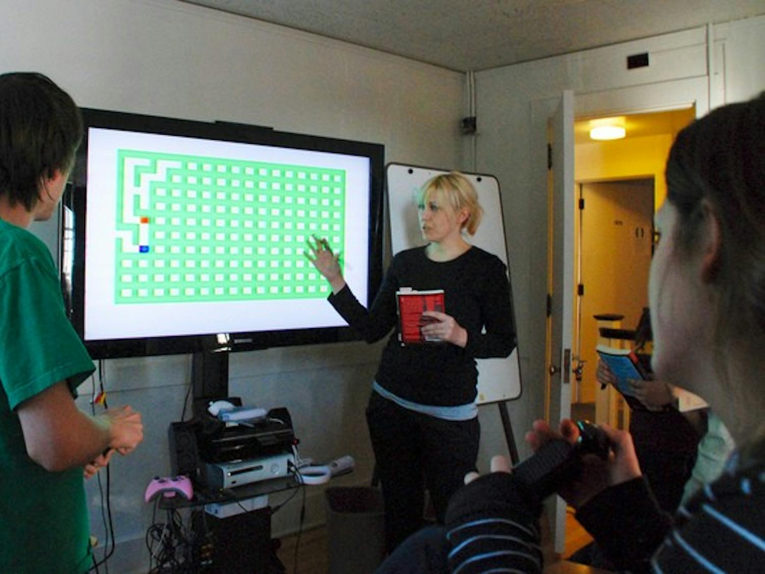 Professor Mary Flanagan and her students examine a vintage video game in the newly-opened Tiltfactor Lab, a game design center in North Fairbanks Hall that houses many antique and modern gaming consoles.