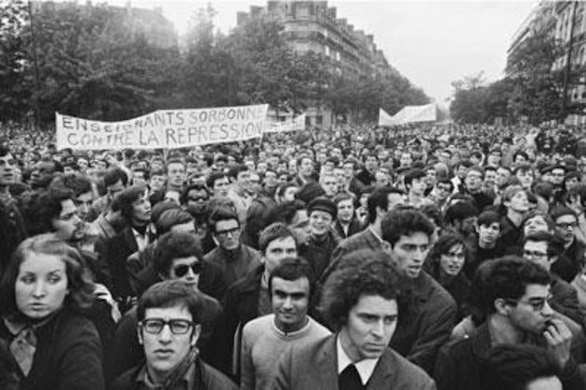 In this photograph, Strambourg captures a crowd of marching protestors holding a sign that reads 