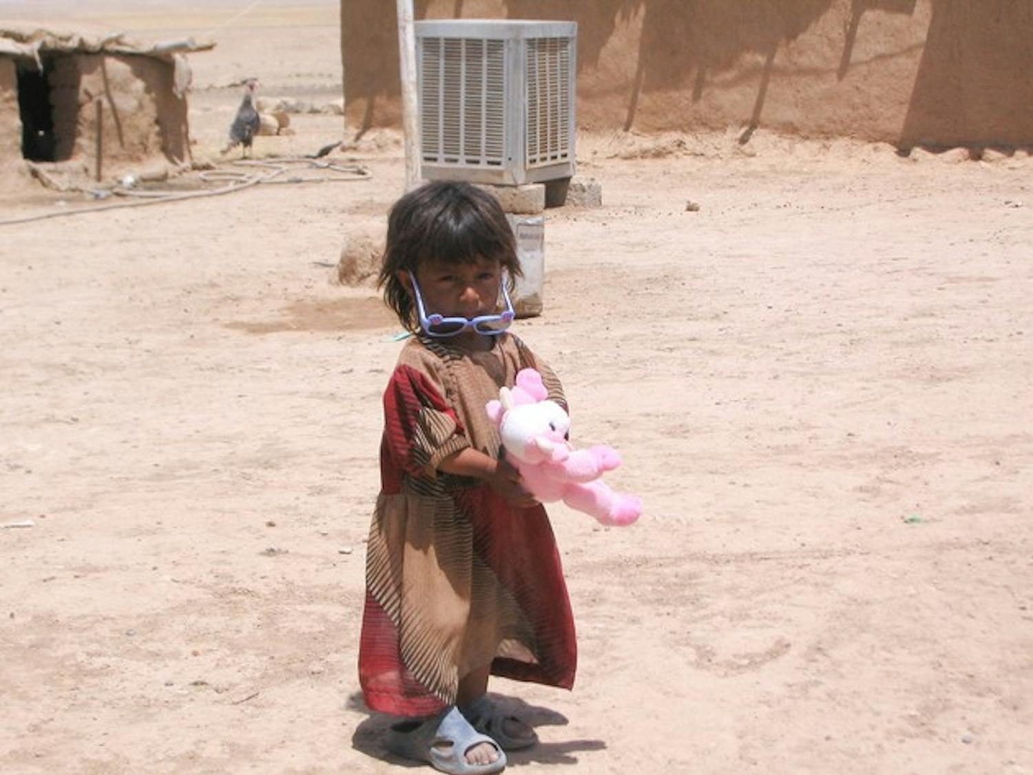 An Iraqi girl clutches a stuffed animal and wears sunglasses donated by the Iraqi Kids Project, which formed three years ago.