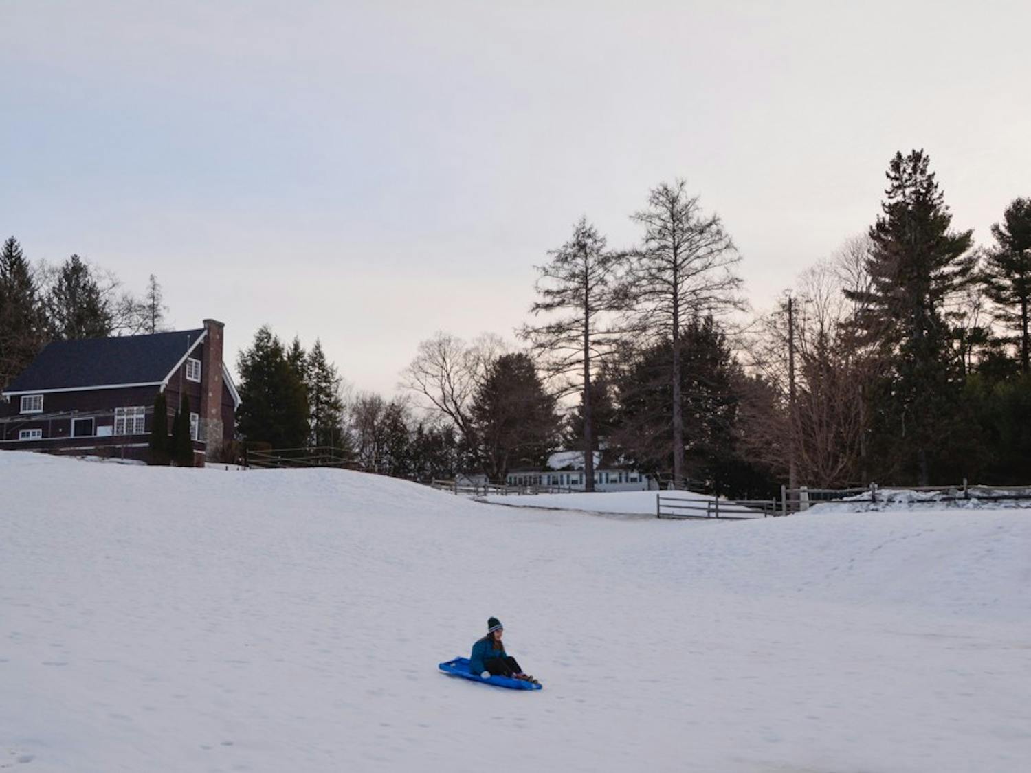 A student takes a study break and goes&nbsp;sledding on the golf course.