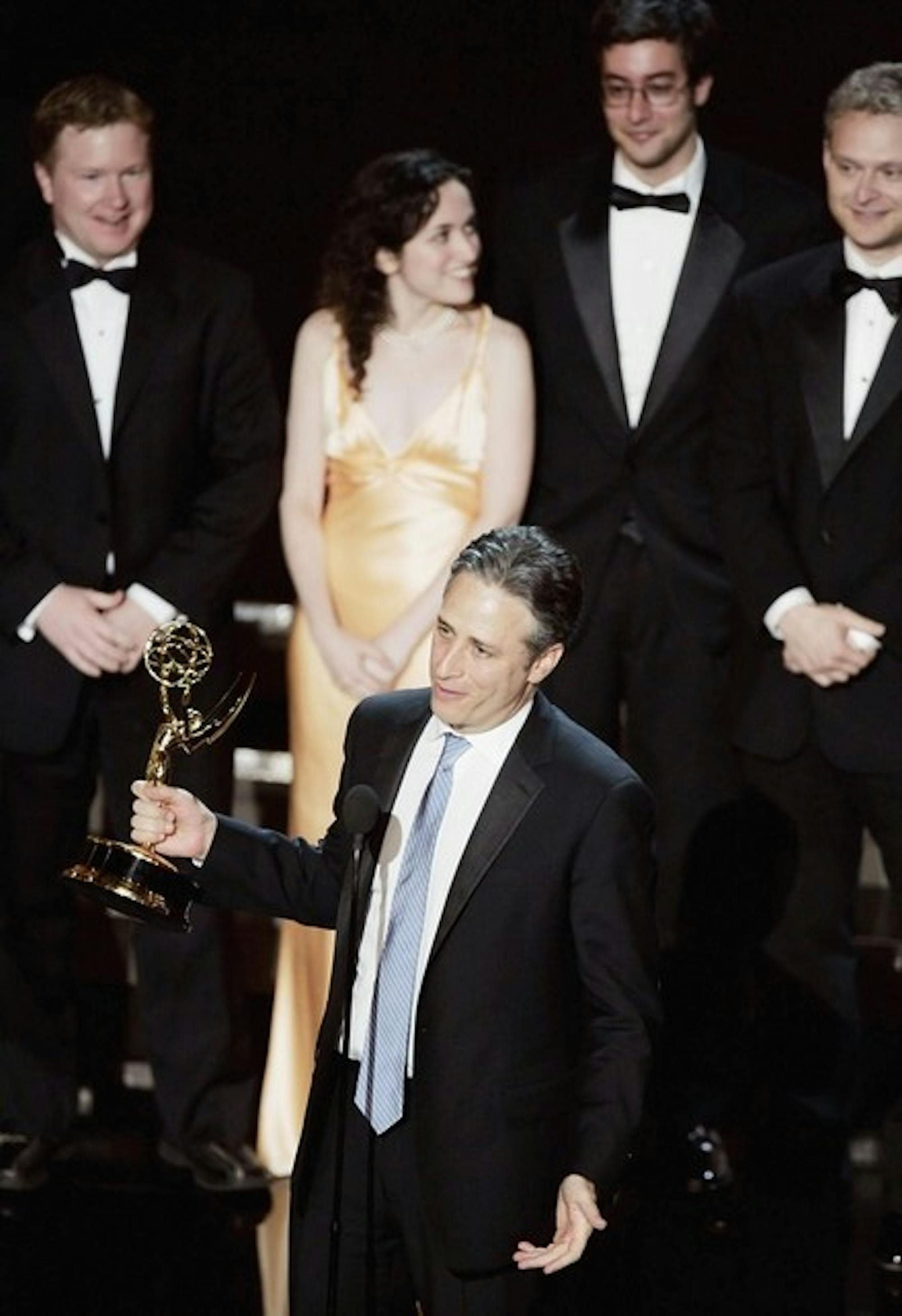 Sam Means '03 (back, center) takes the stage with Jon Stewart to accept an Emmy award for his comedic writing contributions to the popular TV program, 