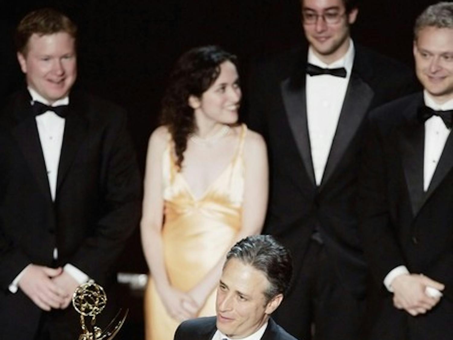 Sam Means '03 (back, center) takes the stage with Jon Stewart to accept an Emmy award for his comedic writing contributions to the popular TV program, 